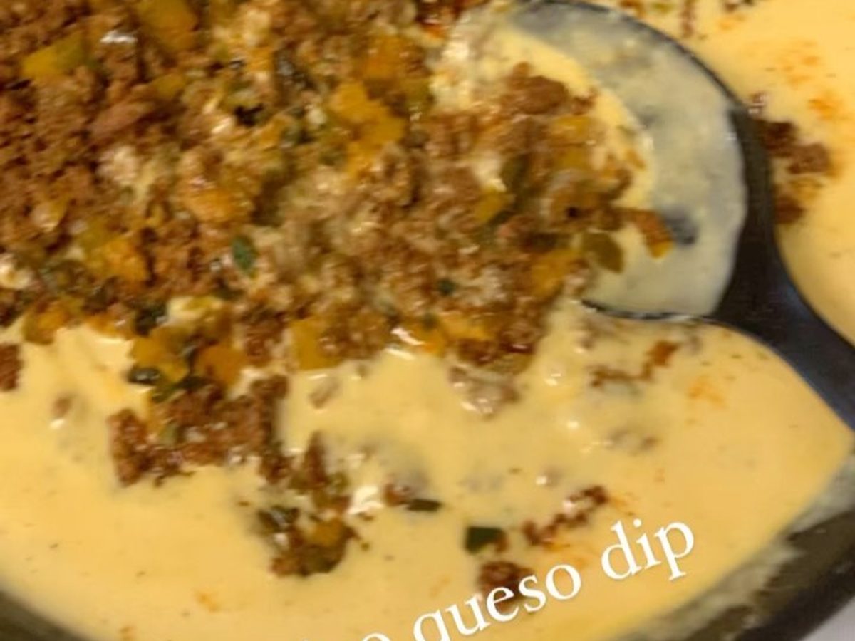 Chorizo queso dip topped with crumbled sausage in a skillet