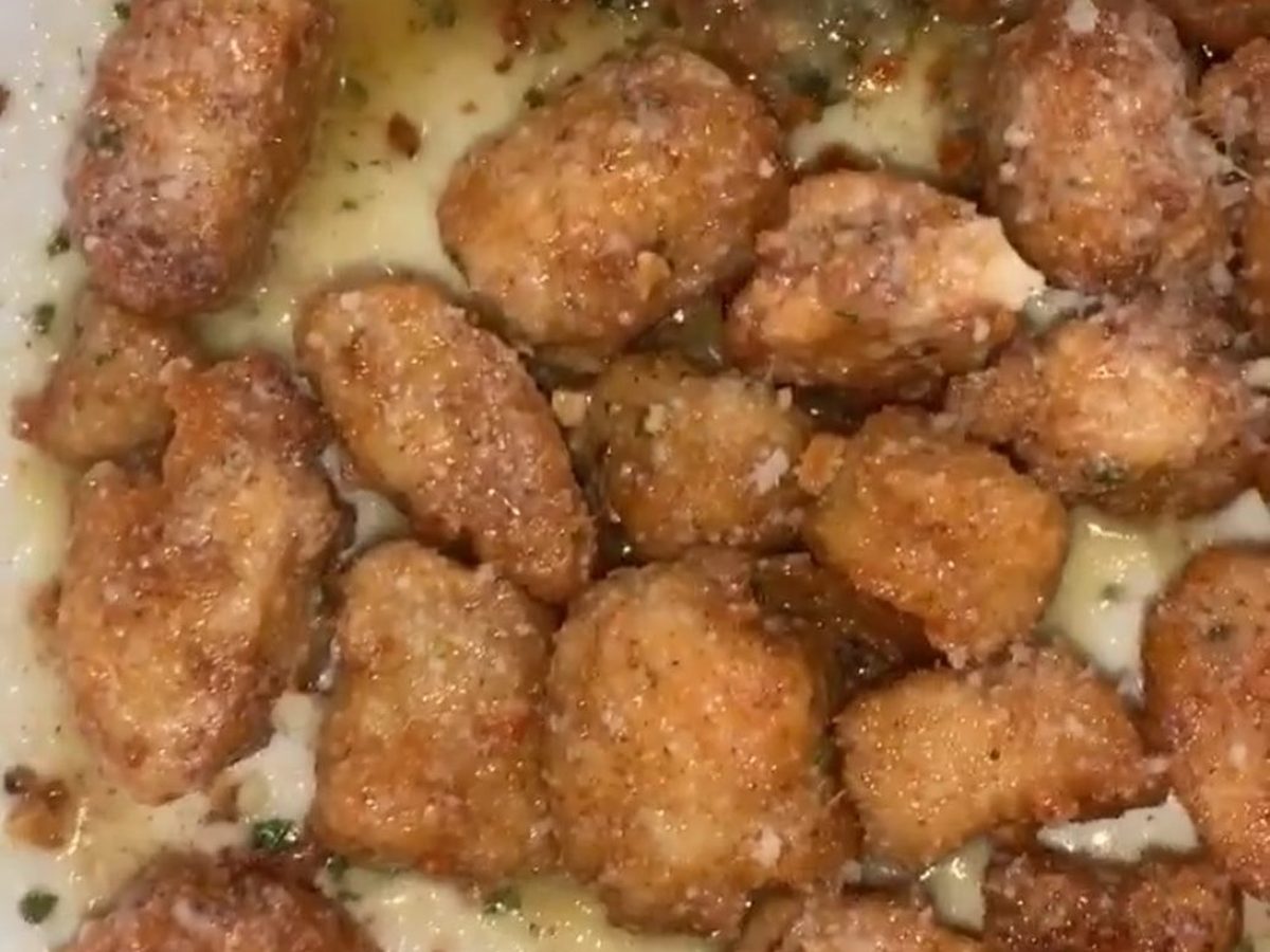 Golden garlic parmesan wings dusted with cheese and parsley in a foil tray