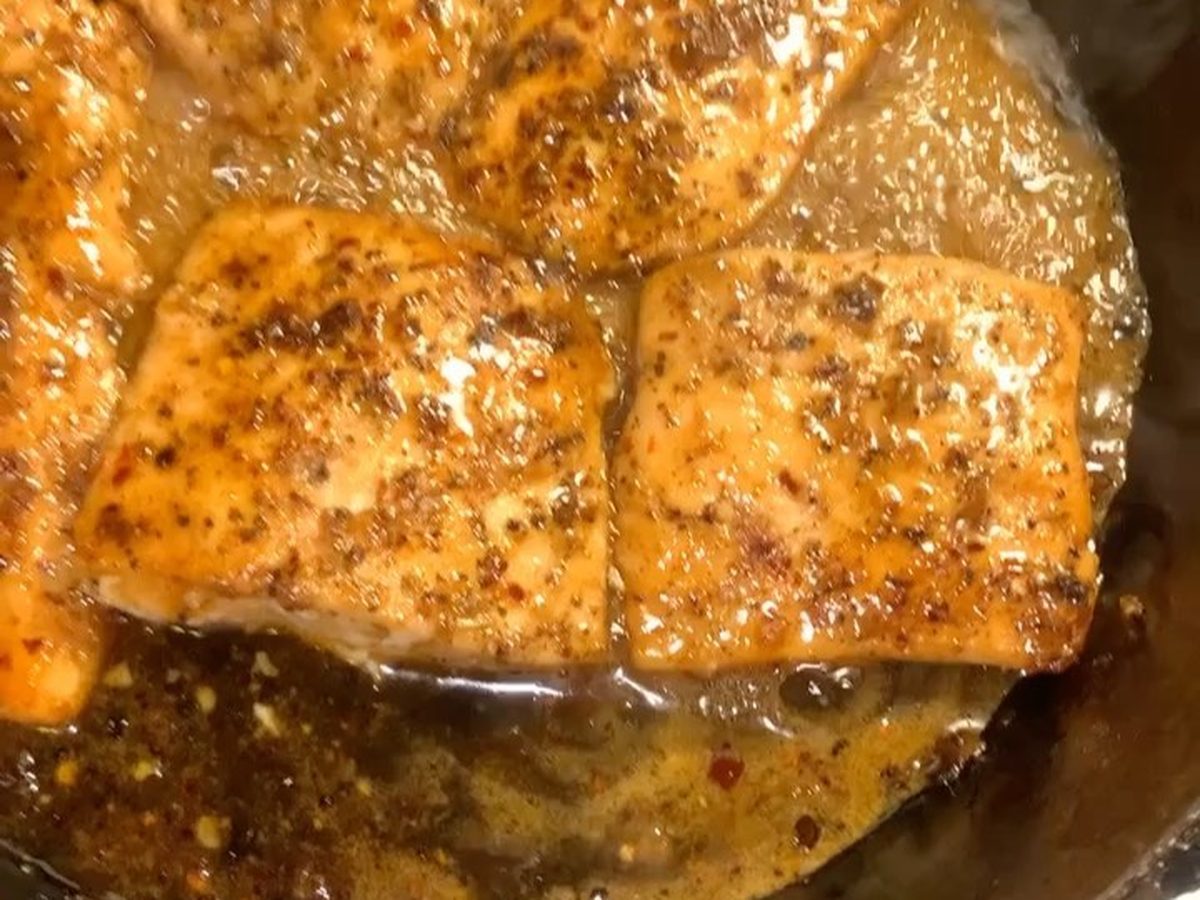 A seared salmon fillet glazed golden in a pan