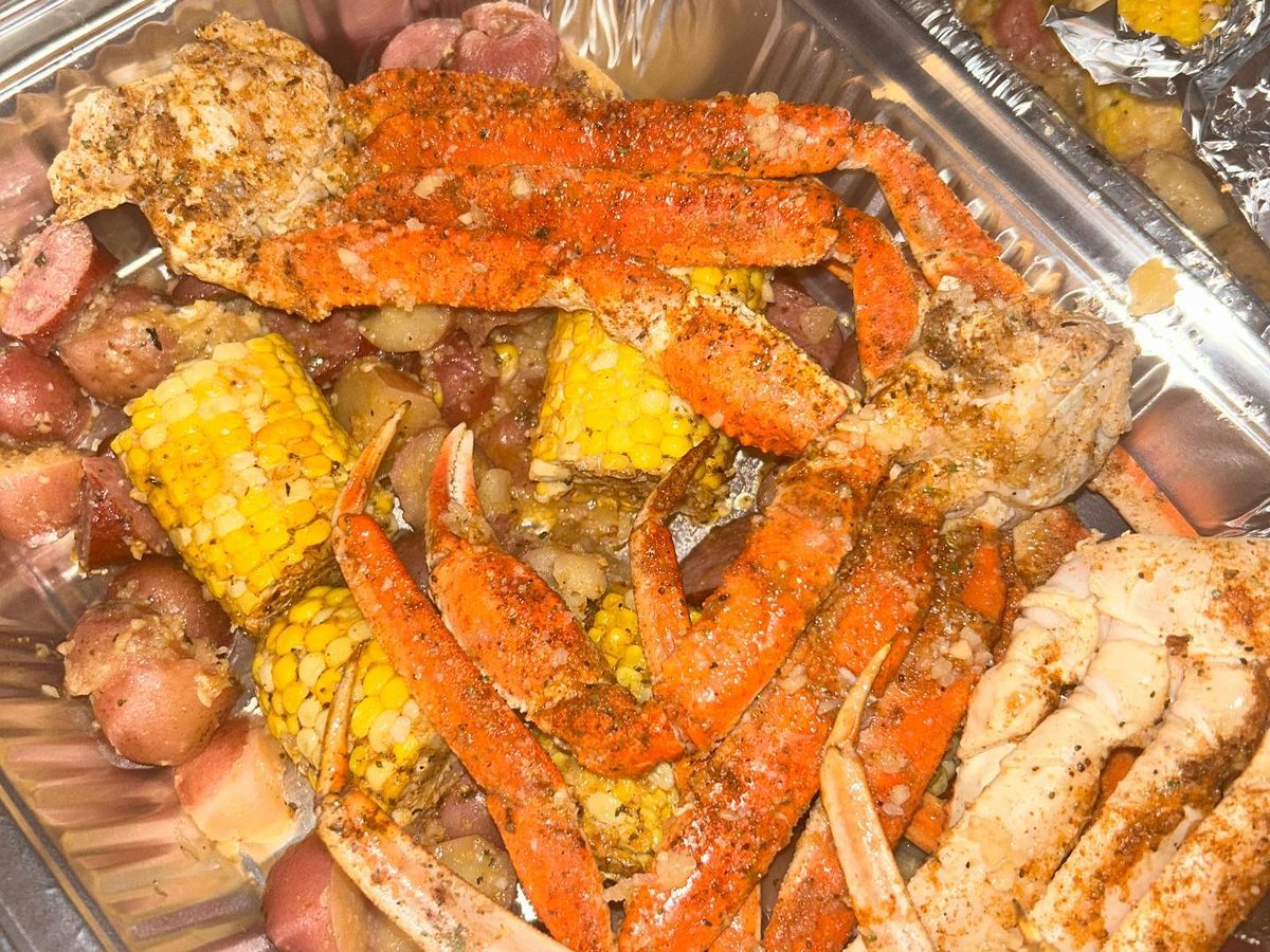 Snow crab clusters, shrimp, corn on the cob and red potatoes seasoned red in a foil tray