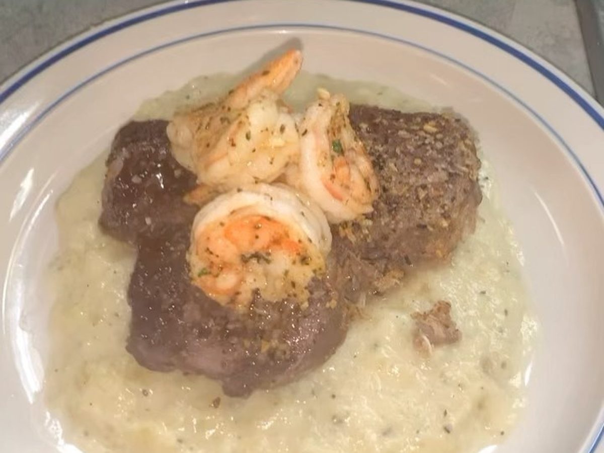 A stuffed steak topped with shrimp sitting on creamy risotto