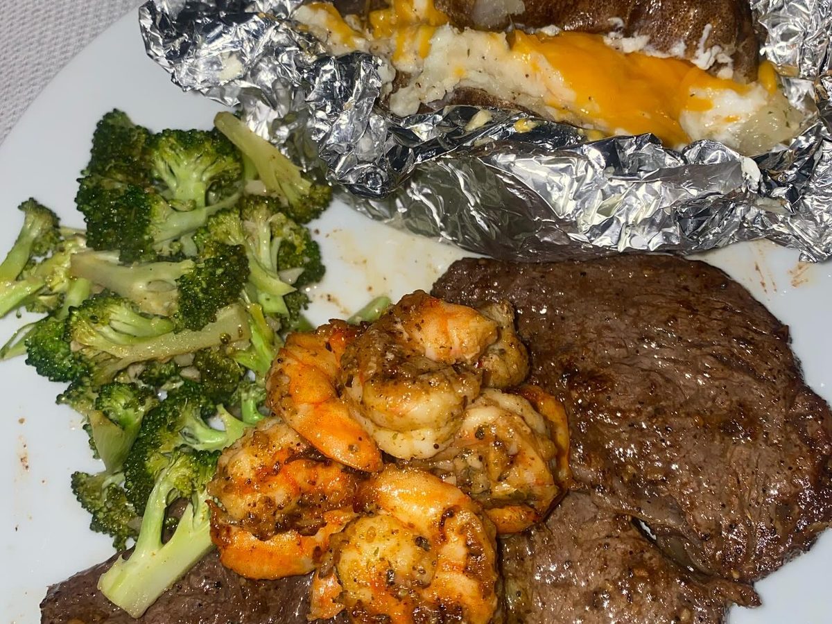 Sliced steak with shrimp, broccoli and sauteed spinach on a plate